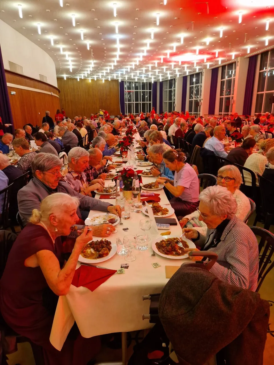 Gasten zitten samen aan een lange feesttafel in het Kursaal tijdens het kerstfeest van 2025.